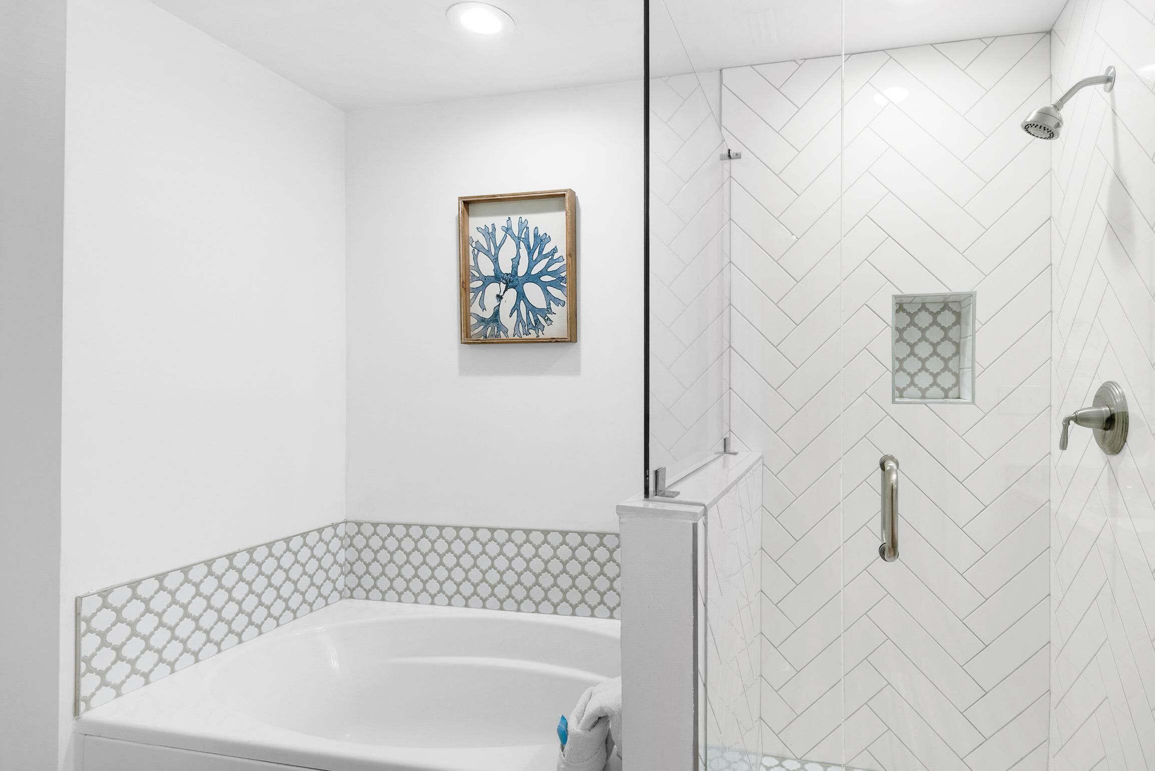 A modern bathroom with a freestanding bathtub, a shower enclosure, and a decorative wall piece.