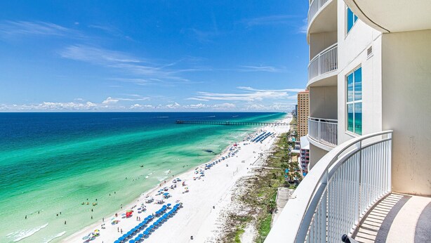 A beachfront hotel with a balcony overlooking the ocean, a pier, and beach umbrellas. - Aqua Resort 1505 (Panama City Beach)