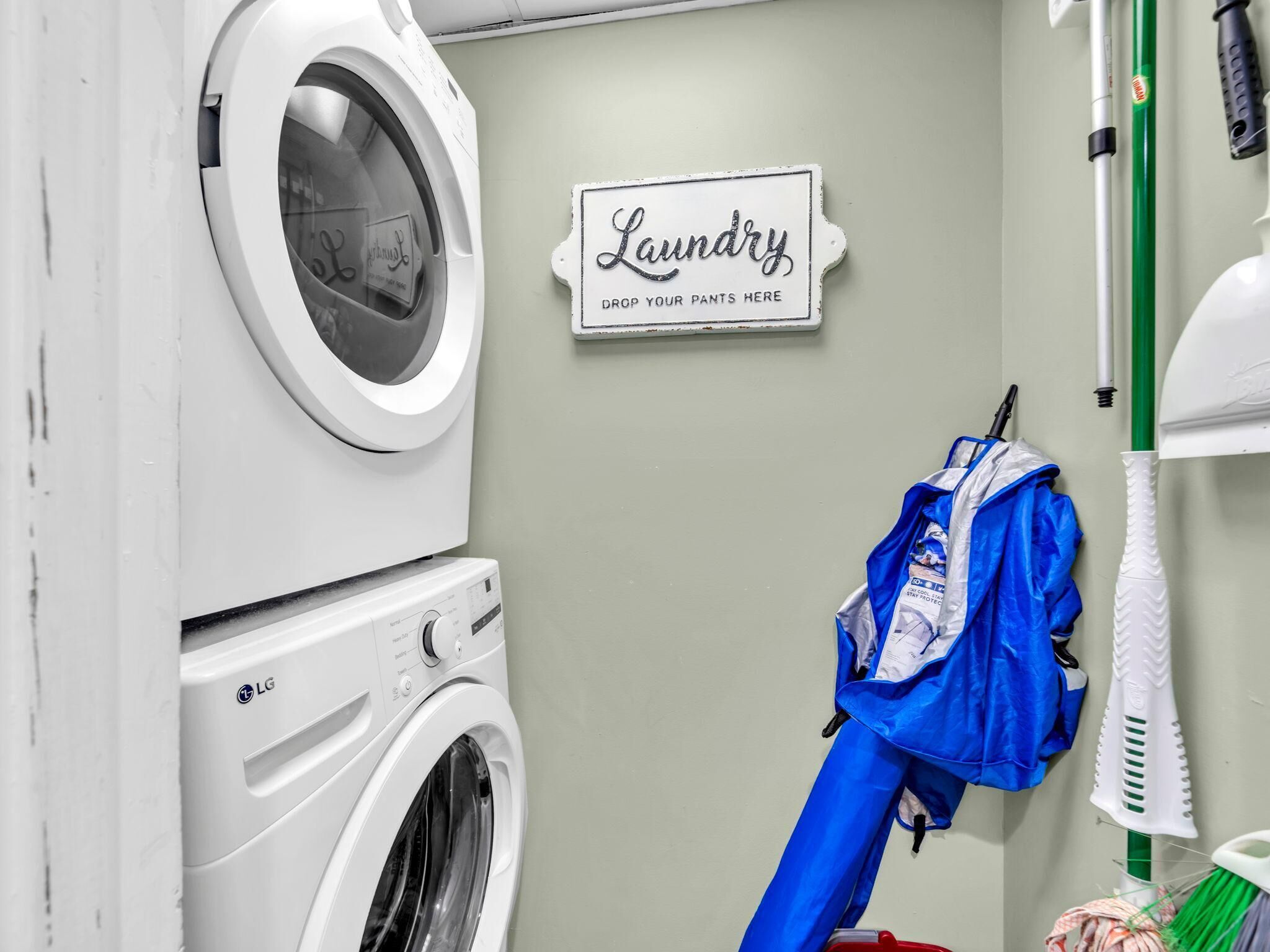 Uma lavanderia com uma placa que diz 'Laundry Drop Your Pants Here' e uma sacola azul pendurada em um gancho.
