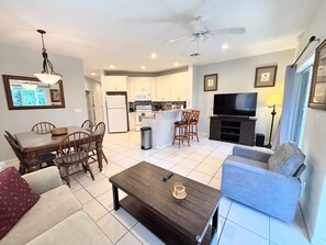 A modern living room with a dining area, kitchen, and a TV.