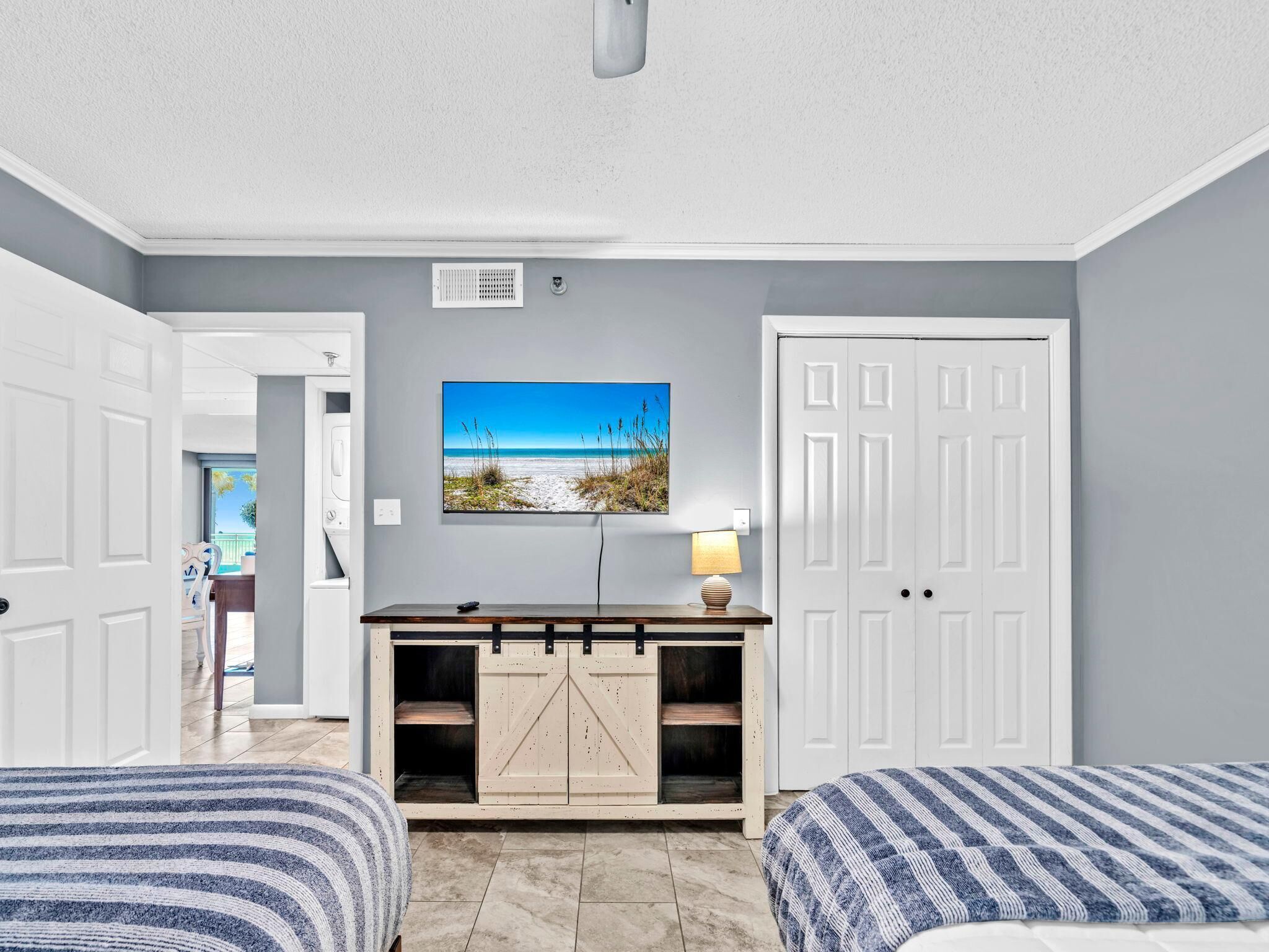 A bedroom with two beds, a TV, a mounted picture, and a door.