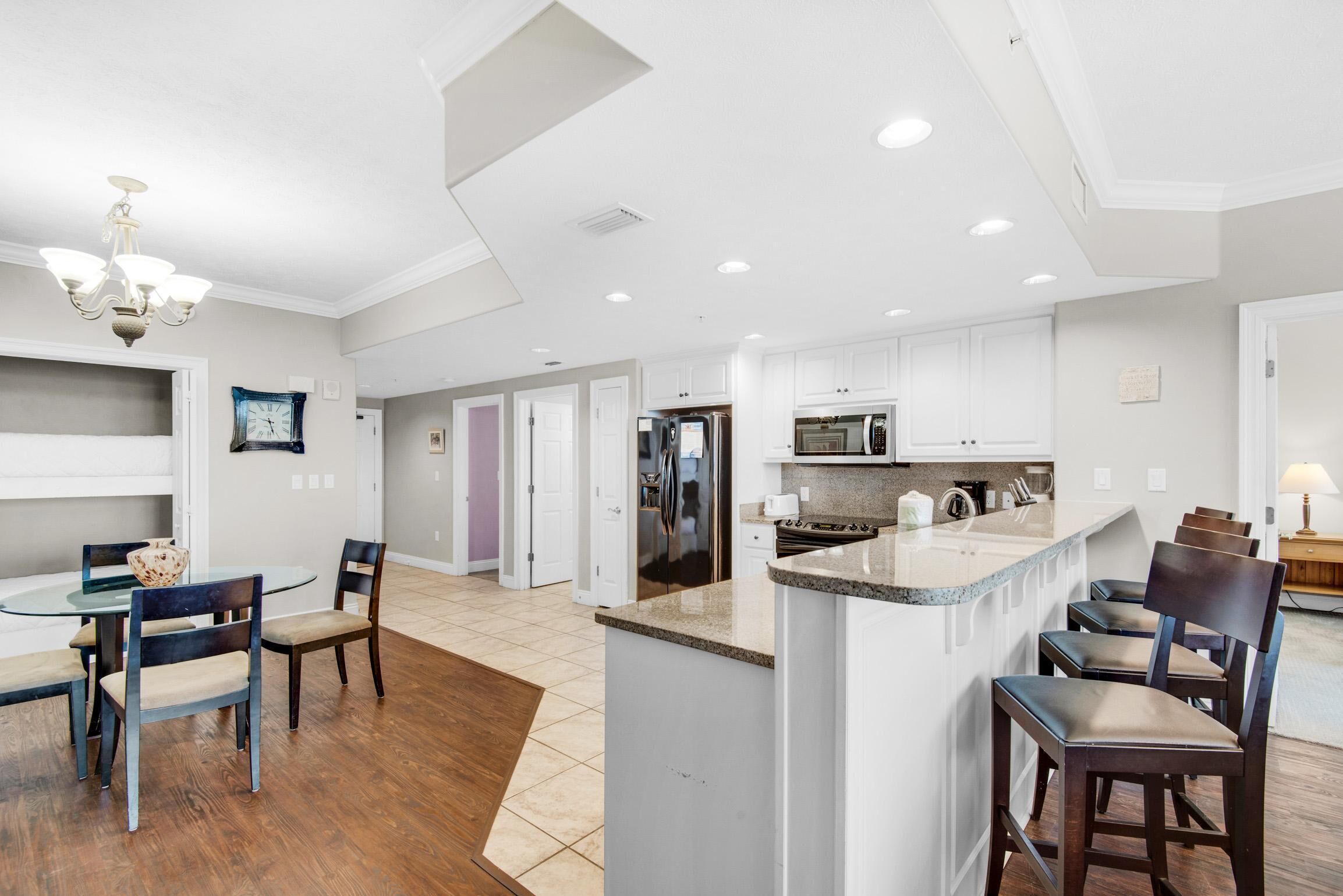 A spacious kitchen with a central island, white cabinetry, and a dining area with a round table and chairs.