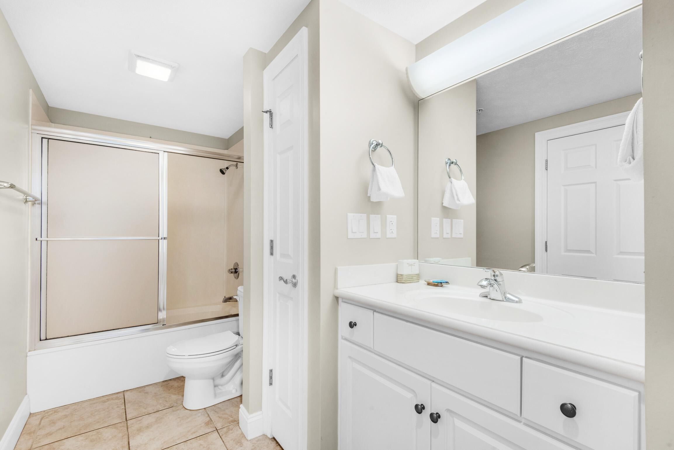 A modern bathroom with a shower, toilet, and vanity with a large mirror.