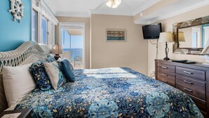 A bedroom with a bed, a ceiling fan, a TV, a dresser, and a sign indicating the room's location. - The Summit 1432 (Panama City Beach)