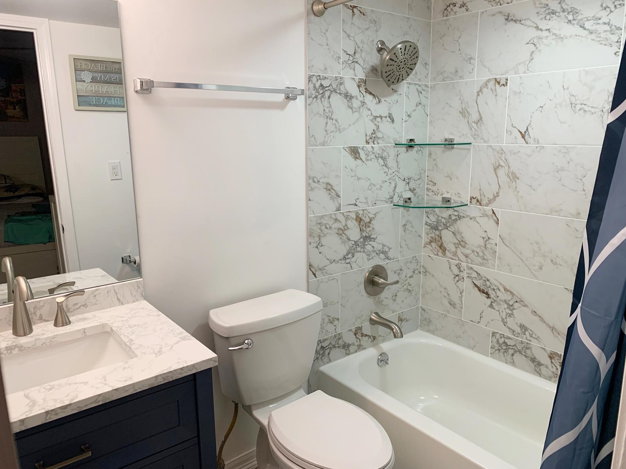 A bathroom with a toilet, sink, and bathtub, all with marble-like tiles.