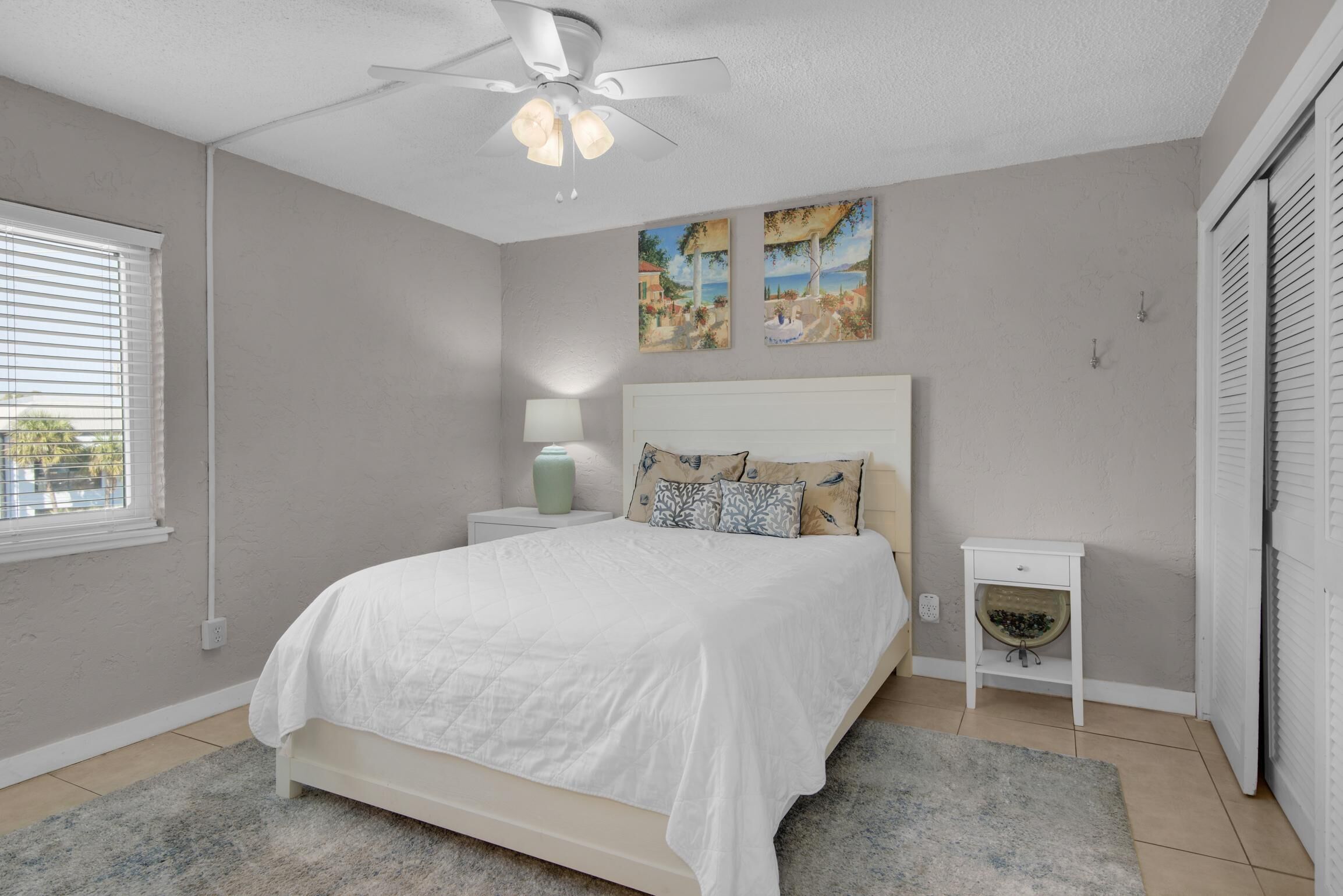 A bedroom with a bed, a nightstand, a lamp, and a ceiling fan.