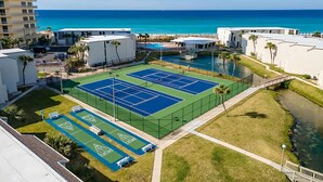 Een tennisbaan omringd door gebouwen, met uitzicht op de oceaan.