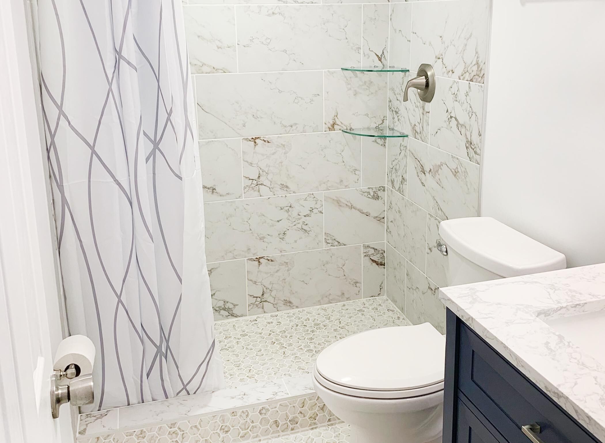 A bathroom with a toilet, shower, and marble tiles.