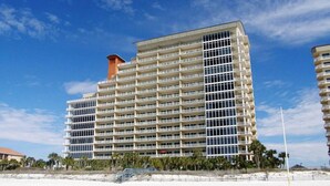 A multi-story hotel with a modern design, featuring balconies on each floor and a prominent central tower.