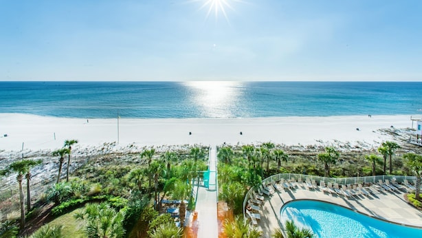 A resort with a pool, beach access, and palm trees.