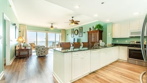 A spacious kitchen with white cabinets, a large island, and a dining area with a view.