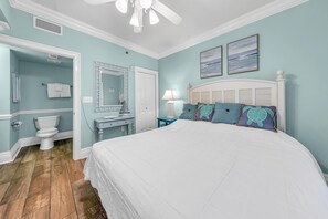 Cozy retreat with a large bed, white-framed headboard, and dresser, set against a light blue backdrop.