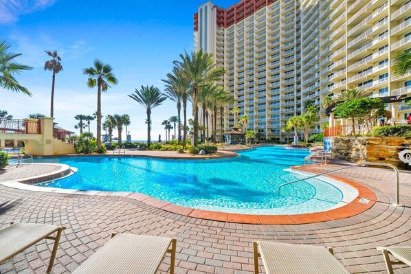 Relax by the resort's large pool surrounded by lounge chairs and palm trees.