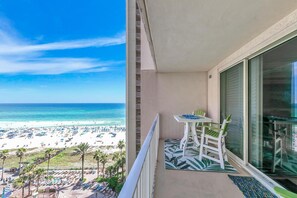 Enjoy the stunning beach views from this balcony with a table and two chairs.
