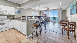 A modern kitchen with white cabinets, a microwave, and a dining area with wooden chairs and a table.