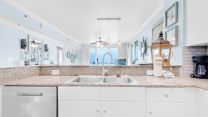 A modern kitchen with granite countertops, stainless steel appliances, and a large window. - Shores of Panama 1401 (Panama City Beach)