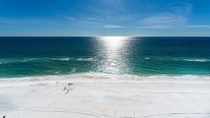 A beach with a clear sky and the sun shining over the ocean. - Shores of Panama 1401 (Panama City Beach)