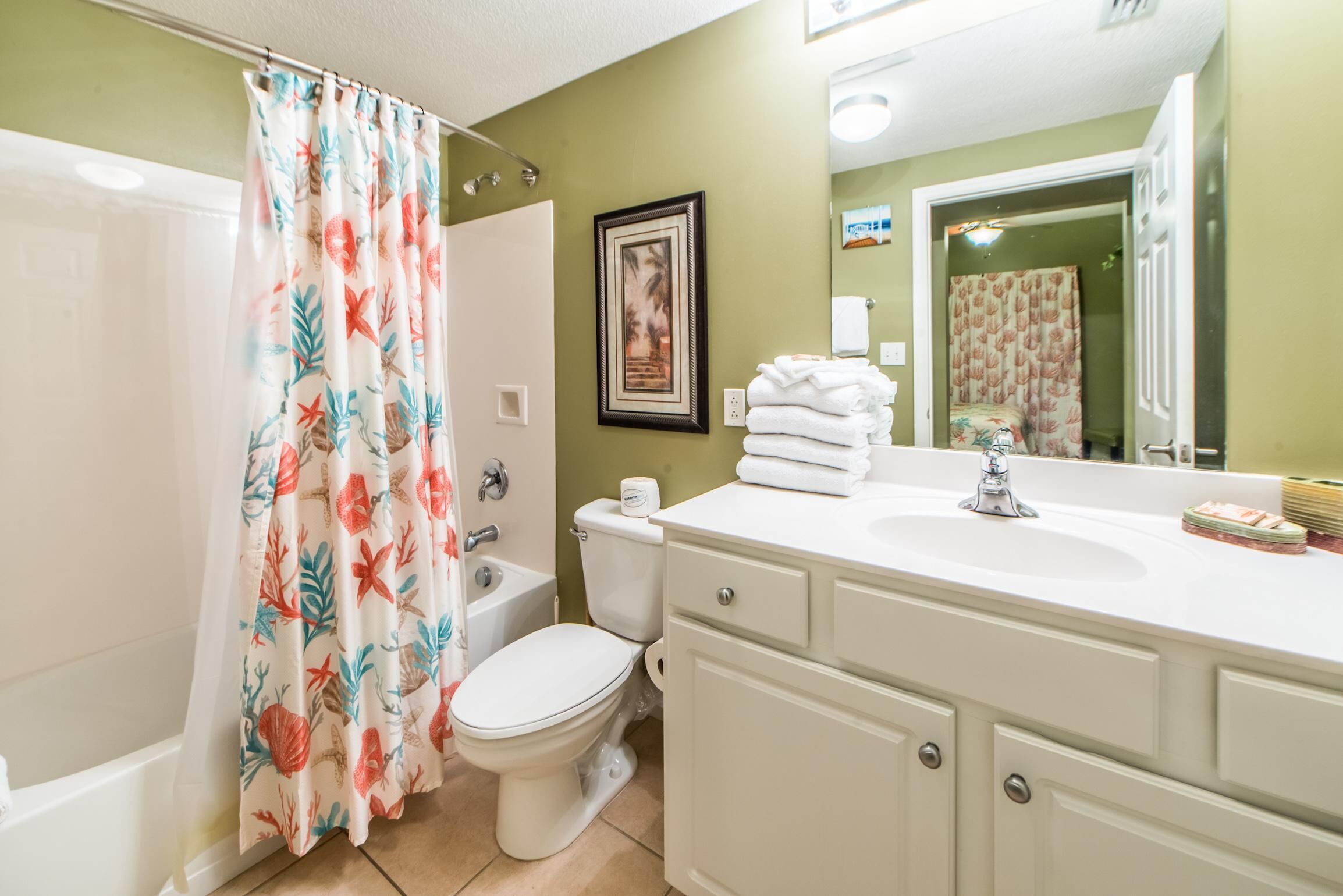 A bathroom with a bathtub, toilet, sink, and a shower curtain with a floral pattern.