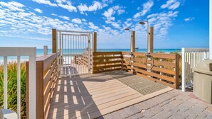 A wooden deck with a view of the ocean, a wooden gate, and a shower area.