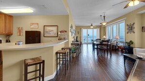 A spacious kitchen with a bar area, wooden flooring, and a dining area with a view.