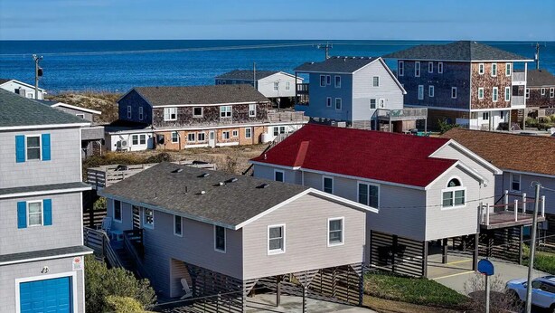Een kustgebied met woonhuizen, een huis met een rood dak en uitzicht op zee.