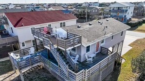 Een tweelaags huis met een terras, zitplaatsen buiten en een kleine trap.