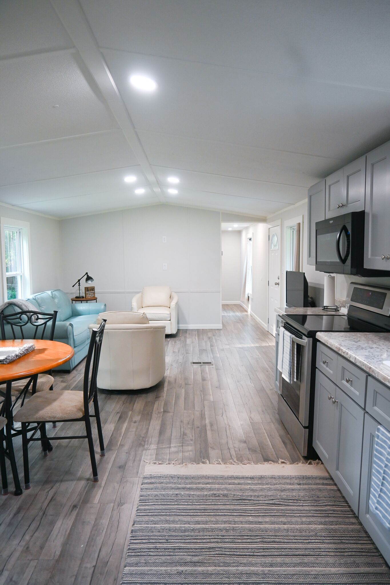 A modern kitchen with a dining area, featuring a wooden floor, a kitchen island, and built-in appliances.