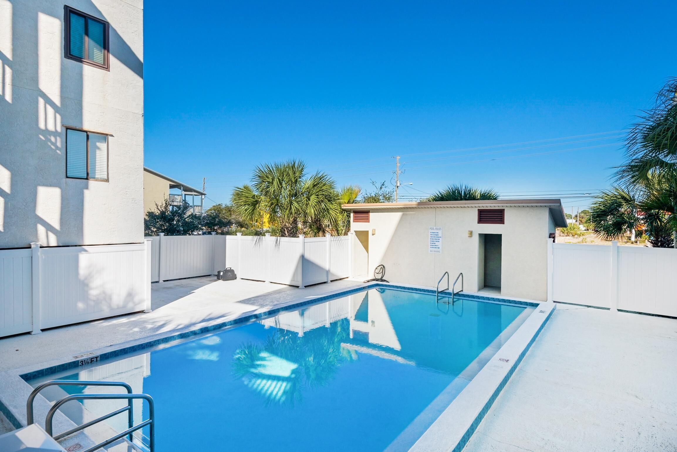 A rectangular swimming pool with a clear blue water surface, surrounded by a white deck.