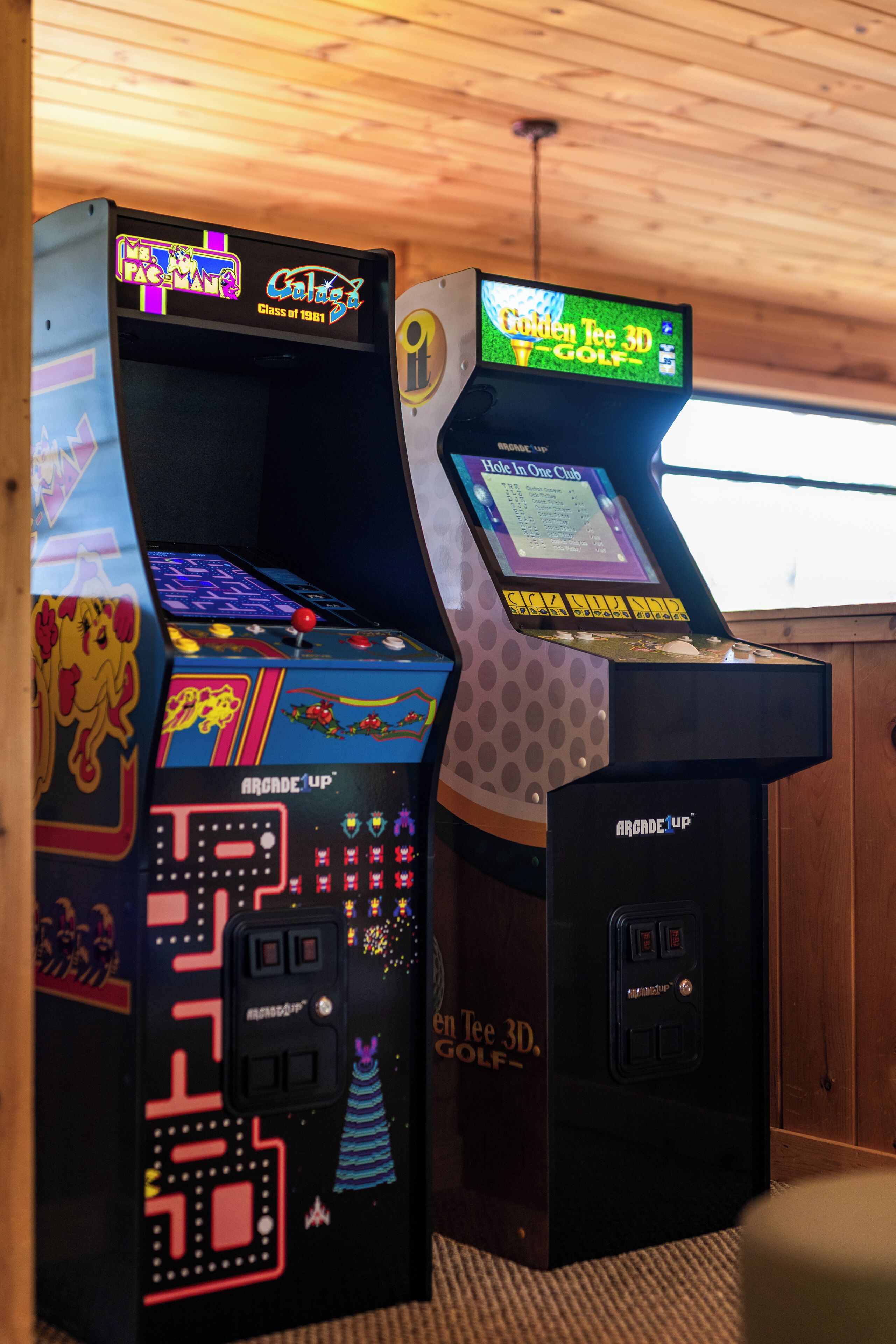 Two arcade machines, one labeled "Galaga" and the other "Hole in One Club."