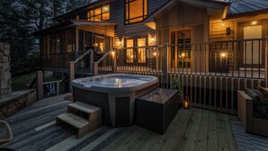 Una terraza de madera con un jacuzzi, asientos al aire libre y una escalera que lleva a un área techada.