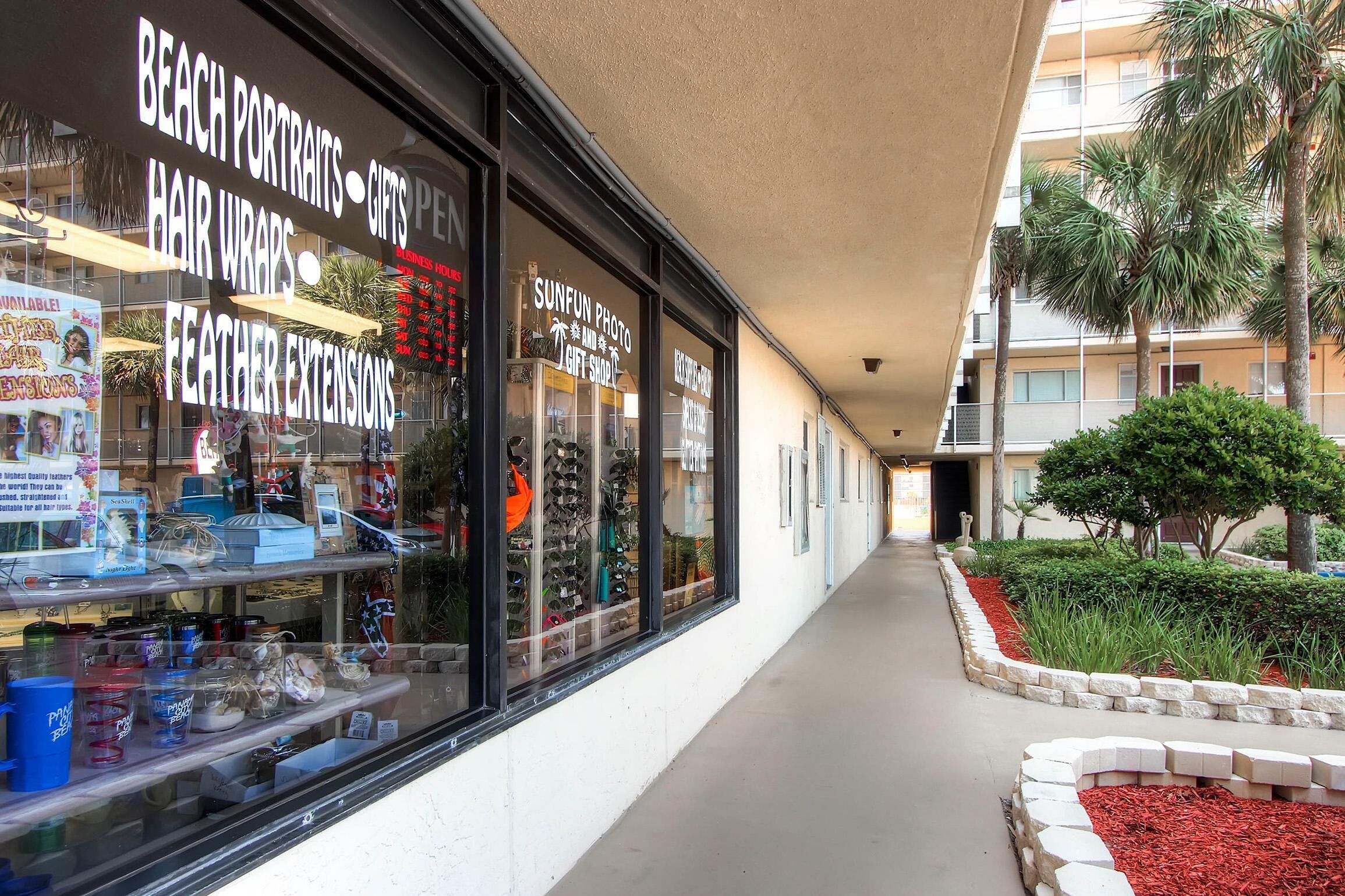 Une devanture de magasin avec des panneaux indiquant : « portraits sur la plage », « coiffures avec des mèches » et « extensions de plumes ».