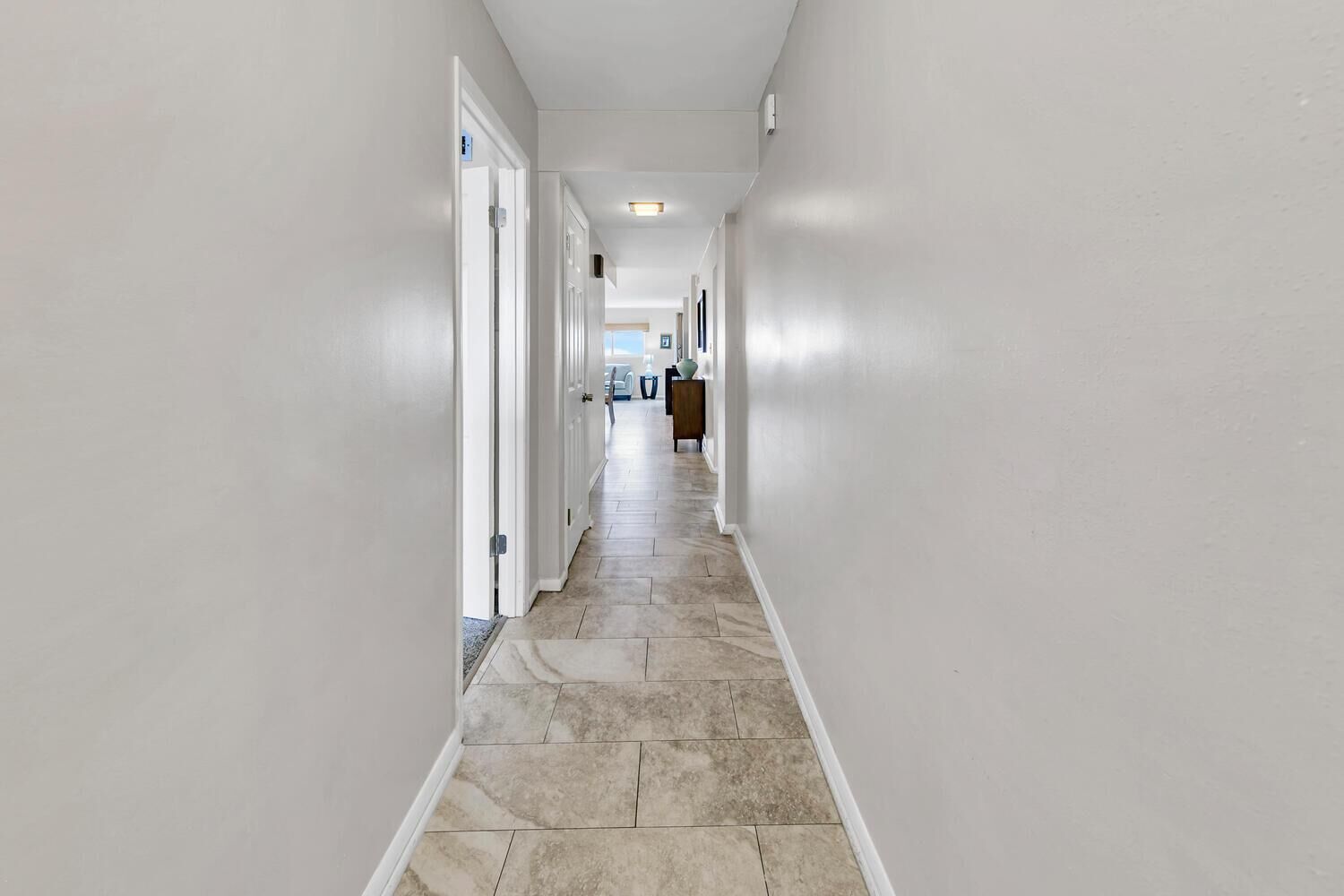 A narrow hallway with white walls and a tiled floor.