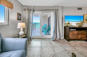 A hotel room with a balcony, a TV, a lamp, and a chair.