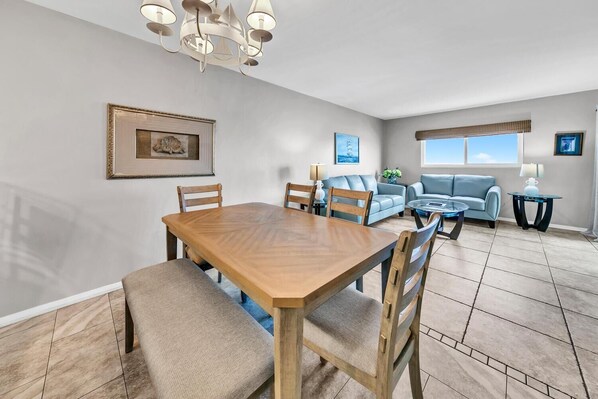 A spacious living room with a wooden dining table, two sofas, and a coffee table. - Regency Towers 623 (Panama City Beach)