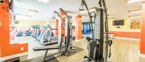 A gym with cardio machines, weight machines, and a bench.
