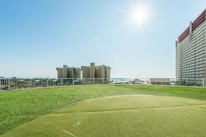 A golf course with a clear sky and buildings in the background. - Laketown Wharf 2118 (Panama City Beach)
