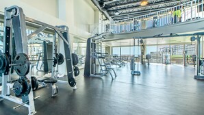 A spacious gym with various weightlifting equipment, a mezzanine level, and a view of the outdoors. - Laketown Wharf 2118 (Panama City Beach)