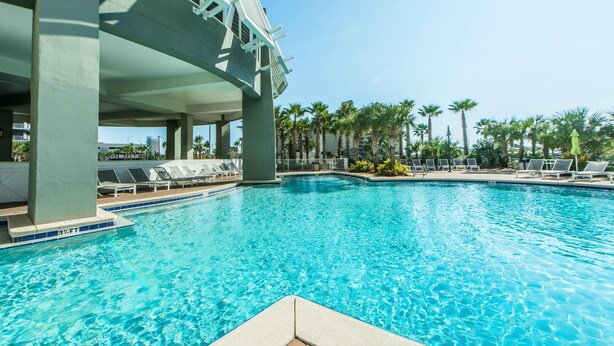 A swimming pool with lounge chairs and palm trees in the background. - Laketown Wharf 2118 (Panama City Beach)