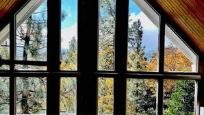 Une pièce dotée de grandes fenêtres donnant sur des arbres et un ciel dégagé.