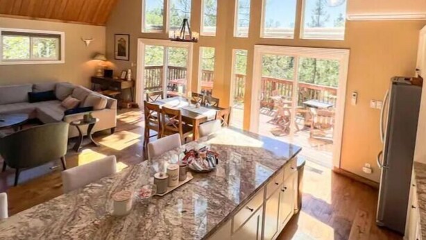 Une cuisine spacieuse dotée d’un grand îlot central, d’un plafond en bois et de grandes fenêtres.