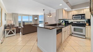 A modern kitchen with a central island, built-in appliances, and a view to the outside. - Perdido Sun 406 (Pensacola)