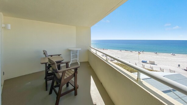 A balcony with a view of the beach, a table, and chairs. - Perdido Sun 406 (Pensacola)