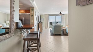Een ruime woonkamer met keuken, eethoek en balkon.