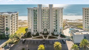 Een hoog hotel met meerdere verdiepingen, een zwembad en uitzicht op het strand.