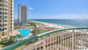 A hotel with a pool, beach view, and a tall building in the background. - Beach Colony Tower 5B (Pensacola)