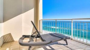Ein Balkon mit einer Korlounge, einem weißen Geländer und Blick aufs Meer.