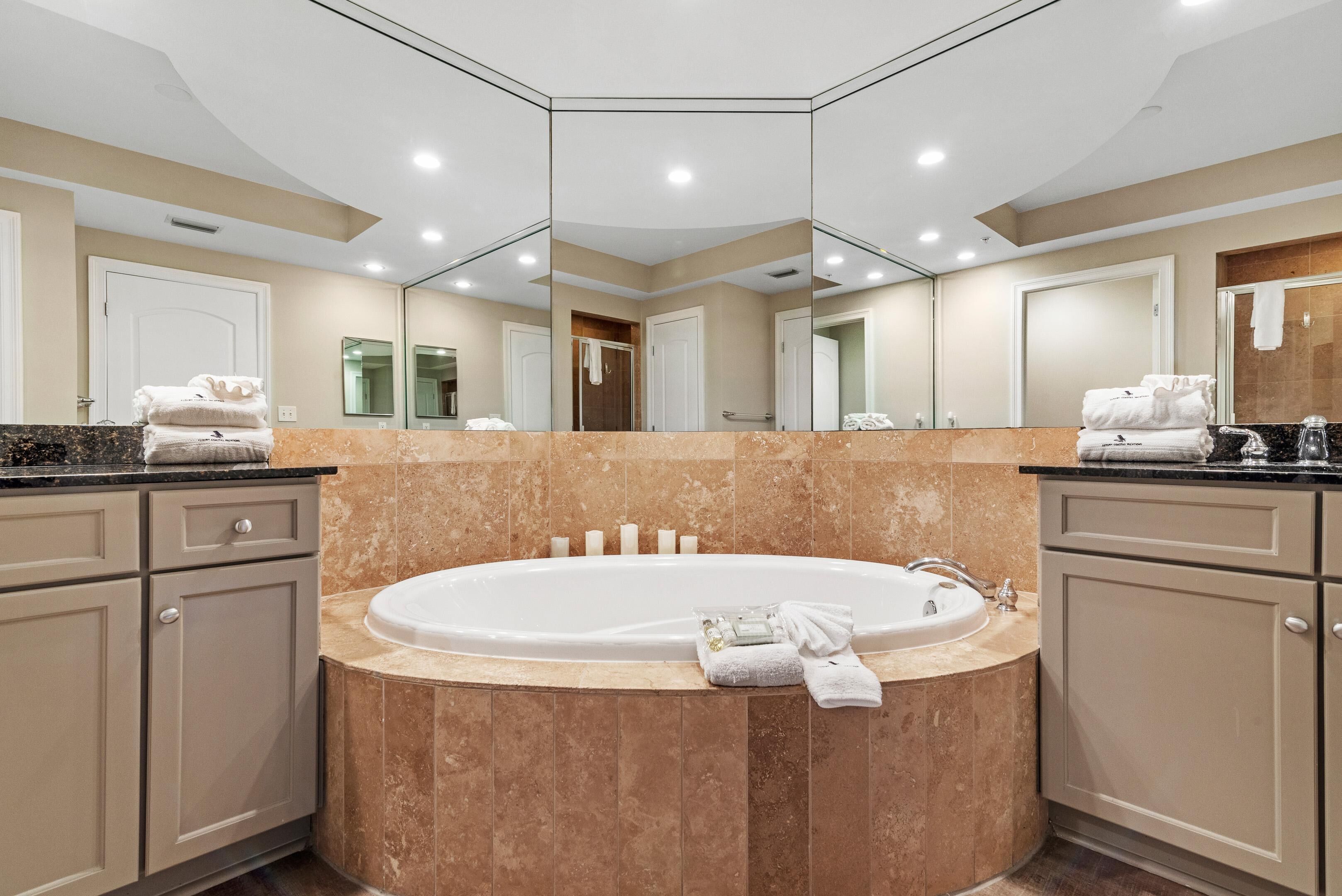 A modern bathroom with a large bathtub, beige tiles, and a mirror above the sink.