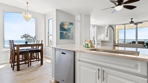 Une cuisine moderne équipée d’un lave-vaisselle, de meubles blancs et d’un grand îlot central.