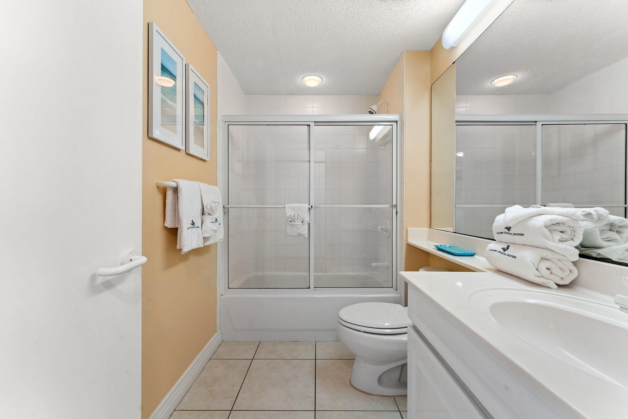 A modern bathroom with a glass-enclosed shower, a white toilet, and a large sink with a mirror.