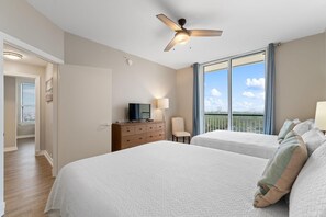 Relax in this stylish room with a large bed, ceiling fan, and comfortable chair, offering a view of the outdoors.